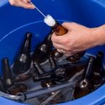 cleaning and sanitizing beer bottles with a solution and a brush