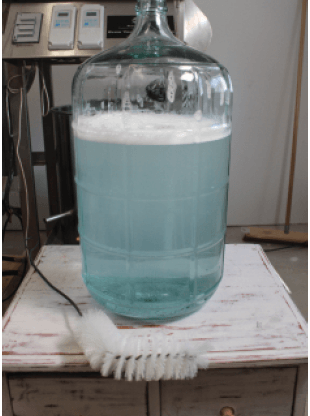 carboy filled with starsan s and a carboy cleaning brush