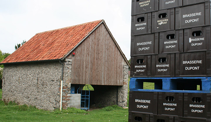Old brick farm building behind cases of beer in crates.