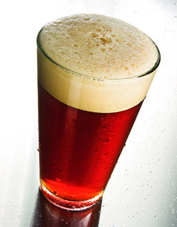 reddish hued clear amber beer with  a tan head in a shaker pint glass 