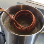 soiled immersion chiller being removed after chilling the wort