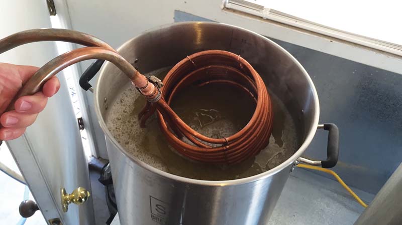 soiled immersion chiller being removed after chilling the wort