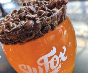 sly fox's morning coffee blonde ale with coffee beans floating on top in the pint glass